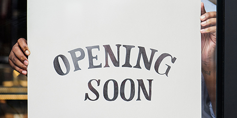 Man hanging opening soon sign in window