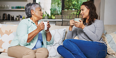 Mature mother and daughter discussing finances over coffee.