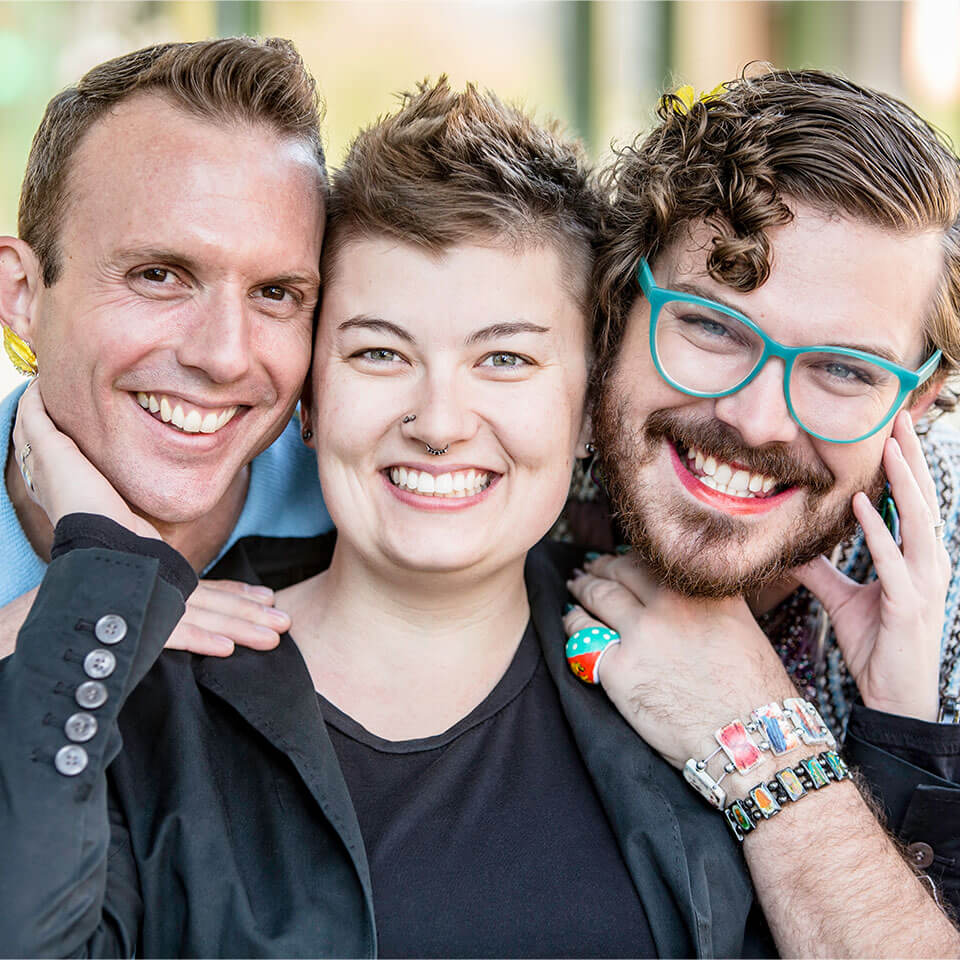 Three gender fluid friends pose and smile for photo.
