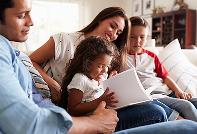 Mother and father reading to daughter and son on couch