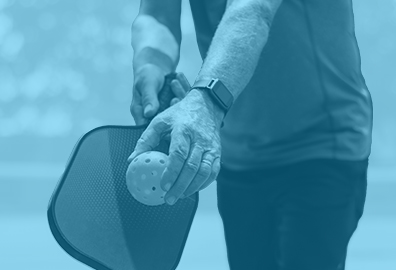 Man holding a pickleball paddle and ball