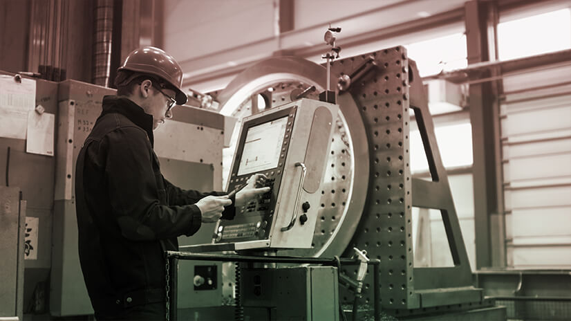 Photograph of male using a touch-interface machine on work floor.