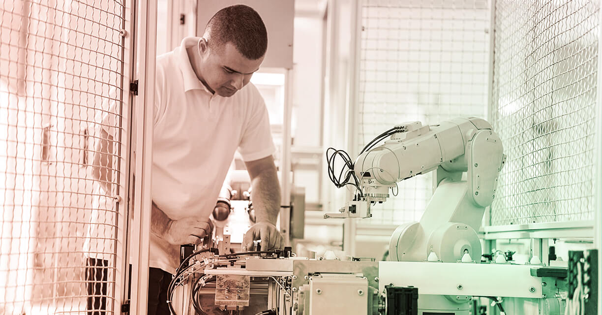 Photograph of man working with industrial robotic machine.